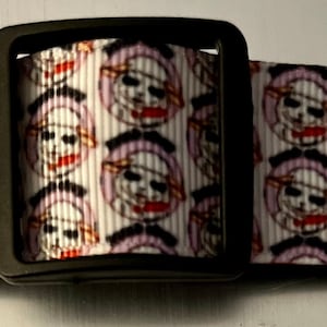 May include: A white and black patterned dog collar with a black metal buckle. The pattern features a repeated image of a cartoon skull wearing a pirate hat.