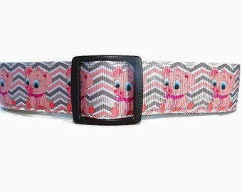 May include: A pink and gray dog collar with a chevron pattern and cartoon pig illustrations. The collar has a black metal buckle.