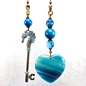 May include: Two blue agate fan pull chains, one with a heart-shaped pendant and the other with a key and seahorse charm.