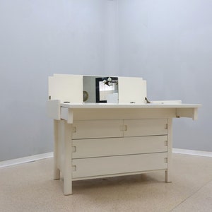 May include: White vanity table with a fold-down top and three drawers. The table has two mirrors on the top.