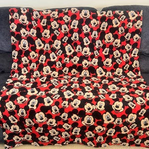 May include: Red fleece blanket with a repeating pattern of Mickey Mouse faces.