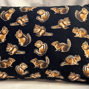 May include: A black pillow with a repeating pattern of brown squirrels. The squirrels are in various poses, some are running, some are sitting, and some are looking up.