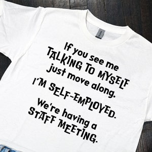 Puede incluir: Camiseta blanca con texto negro que dice "Si me ves hablando conmigo mismo, simplemente pasa de largo. Soy autónomo. Estamos teniendo una reunión de personal."