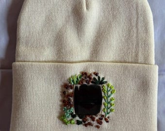 Hand bestickte Strickmütze - Hafermilch mit Blümchen, Herzchenaufnäher-Logo