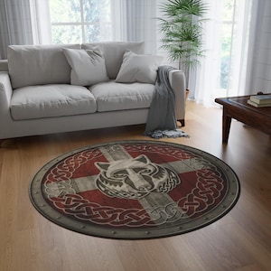 May include: A circular rug with a wolf head motif. The rug displays a red and white cross design, with a wolf's head at the centre, encircled by a grey Celtic knot border. The rug has a distressed, vintage appearance.