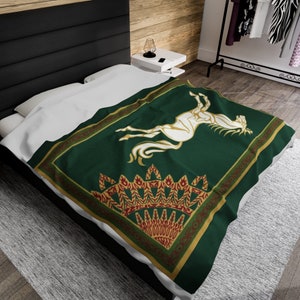 Puede incluir: Una manta de tiro verde con un diseño de caballo blanco y ribetes dorados y rojos. El caballo se levanta sobre sus patas traseras con la cabeza girada hacia un lado. El ribete es un patrón decorativo de hojas y flores.