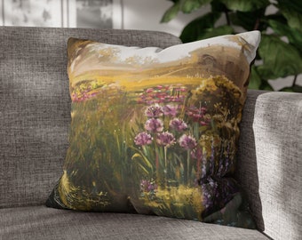 May include: A throw pillow with a watercolor-style print of a field of wildflowers. The pillow features a soft, muted color palette of greens, yellows, and purples.