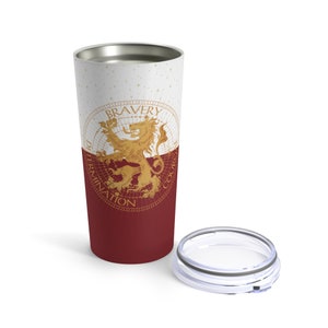 May include: A stainless steel tumbler with a white and burgundy design. The tumbler features a gold lion with the words "Bravery, Determination, Courage" around it.