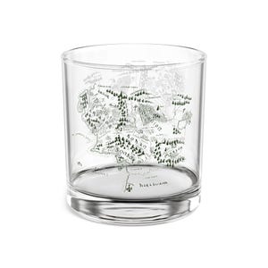 May include: A clear, cylindrical glass with a detailed map design. The map is in shades of green and depicts a fantasy landscape. The glass is suitable for beverages and has a sturdy base.