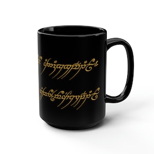 May include: Black ceramic mug with a gold inscription of the One Ring inscription from The Lord of the Rings. The inscription reads "One Ring to rule them all, One Ring to find them, One Ring to bring them all and in the darkness bind them."