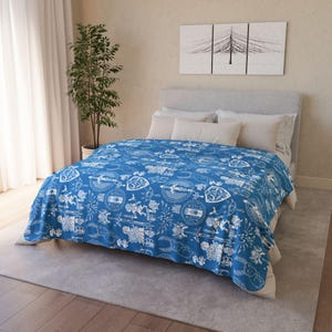 May include: A blue and white patterned duvet cover with a design featuring swords, shields, and other symbols. The duvet cover is on a bed with white pillows.