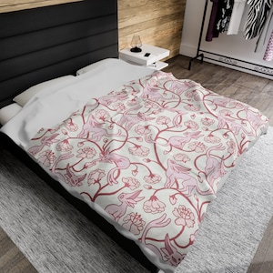 May include: A white and pink bedding set with a floral pattern featuring pink stylized animals. The bedding is on a bed with a black headboard.