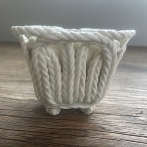 May include: White ceramic planter shaped like a woven basket with four feet.