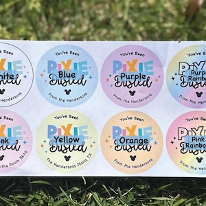 May include: A sheet of eight colorful round stickers with the text "You've Been Pixie Dusted" in various colors. Each sticker has a different color name, such as white, blue, purple, pink, yellow, orange, and rainbow. The stickers also include the text "From the Hendersons" and a Mickey Mouse icon.