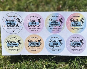 Puede incluir: Hoja de ocho pegatinas circulares con fondos pastel y las palabras "You've Been Pixie Dusted". Cada pegatina tiene un color diferente y el texto "The Johnson Family Room 6713."