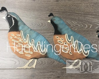 May include: Four decorative quail figurines in varying sizes, arranged in a row. The birds feature teal and brown colouring with white accents and a black crest. The image includes the text "HummingbirdDesigns.com".