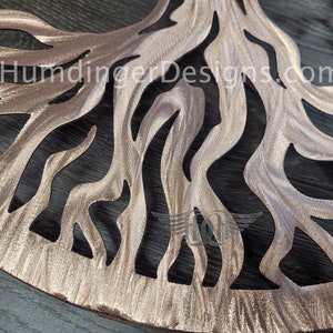 K&ouml;nnte beinhalten: Ein Wandkunstwerk aus Metall in Form eines Baumes mit einer braunen, metallischen Oberfl&auml;che. Der Baum hat ein gro&szlig;es, kompliziertes Wurzelsystem mit einem Ausschnittmuster. Der Hintergrund ist eine dunkle Holzoberfl&auml;che. Der Text "HumdingerDesigns.com" ist im Bild sichtbar.