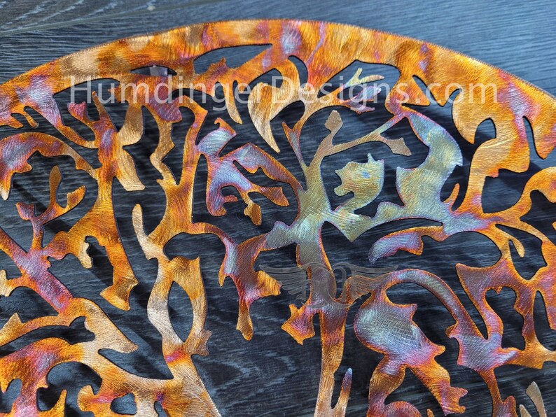 K&ouml;nnte beinhalten: Ein Wandkunstwerk aus Metall, das einen Baum mit filigranen &Auml;sten und Bl&auml;ttern darstellt. Das Metall wurde behandelt, um eine farbenfrohe, irisierende Oberfl&auml;che mit Orange-, Blau- und Violettt&ouml;nen zu erzeugen.