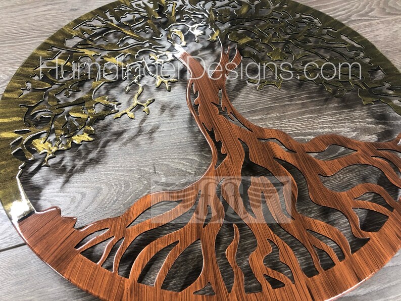 May include: A metal tree of life wall art with a gold and brown finish. The tree has intricate branches and roots. The background is a wood grain pattern.