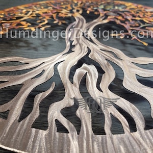 K&ouml;nnte beinhalten: Eine Wandkunst aus Metall in Form eines Lebensbaums mit einer Kupfer-Oberfl&auml;che. Der Baum hat ein detailliertes Design mit filigranen &Auml;sten und Wurzeln. Die Wurzeln sind in einem kreisf&ouml;rmigen Muster ausgebreitet.