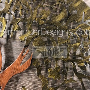 May include: A gold metal tree wall art with a brown wooden trunk. The tree has a detailed design with intricate branches and leaves. The metal has a textured finish.