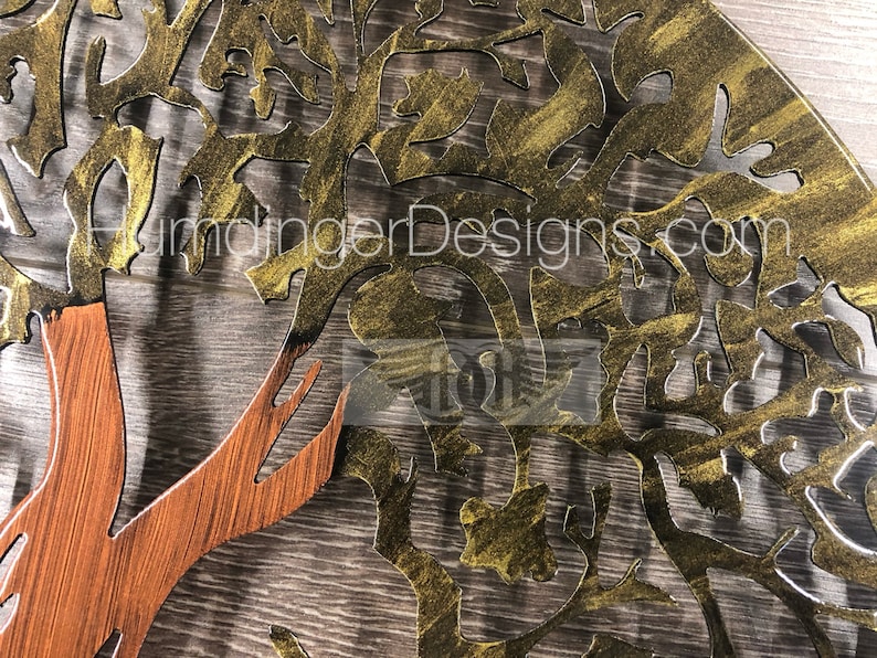May include: A gold metal tree wall art with a brown wooden trunk. The tree has a detailed design with intricate branches and leaves. The metal has a textured finish.