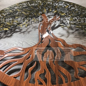 May include: A circular metal wall art piece depicting a tree of life with intricate branches and roots. The tree is cut out of the metal, revealing a wood-grain pattern underneath. The top half of the tree is painted gold, while the bottom half is painted brown.