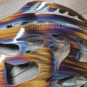 May include: A metal wall art piece in the shape of a butterfly with a blue, purple, and orange iridescent finish. The piece is cut out and has a detailed design.