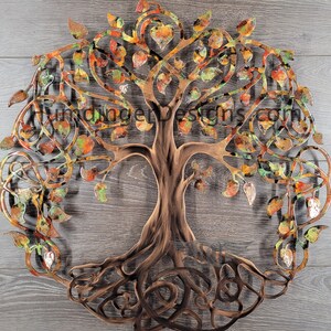 May include: A metal tree of life wall art with intricate branches and roots. The tree is painted in shades of brown, green, and orange, with a heart-shaped design at the top.