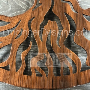 May include: A wooden wall decor in the shape of a tree with intricate cutouts of branches and roots. The wood has a brown stain and a glossy finish. The text "HumangerDesigns.com" is visible on the decor.