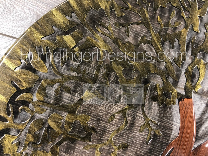 May include: A gold metal tree wall art with a brown wood base. The tree has a detailed design with intricate branches and leaves. The wall art is a decorative piece for a home or office.