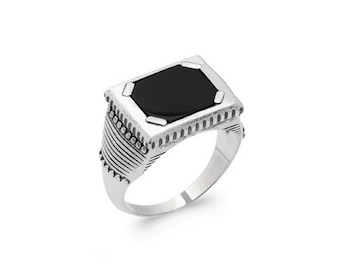May include: A silver ring with a black rectangular stone set in a detailed frame. The ring is marked "BIJOUX ARGENT *** 925 ***".