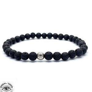 May include: A black lava rock beaded bracelet with a silver charm featuring an eye design.