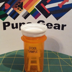 May include: Orange plastic container with a white lid. The container is labeled "Stool Sample".