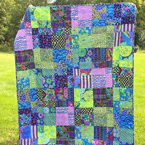 May include: A rectangular patchwork quilt featuring a vibrant array of fabric squares in shades of lime green, royal blue, purple, and teal. The quilt displays various patterns including polka dots, stripes, floral motifs, and geometric shapes.