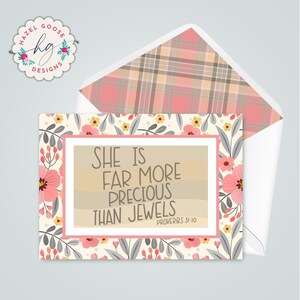 Op de afbeelding: Wenskaart met een bloemenontwerp en de tekst "SHE IS FAR MORE PRECIOUS THAN JEWELS" uit Spreuken 31:10. De kaart heeft een roze en witte rand en een geruite envelopvoering. Het Hazel Goose Designs-logo staat in de linkerbovenhoek.