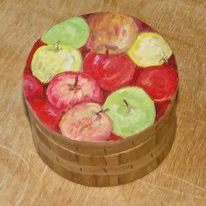May include: A round wooden box with a painted design of red, green, and yellow apples. The box has a lid and is made of wood.