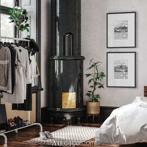 May include: A black tiled wood-burning stove with a gold trim in a room with a white rug, a potted plant, and two black framed prints on the wall.
