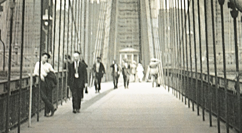 Puede incluir: Fotograf&iacute;a en blanco y negro de personas caminando por un puente. El puente tiene cables verticales y una pasarela. Varias personas caminan en la misma direcci&oacute;n.