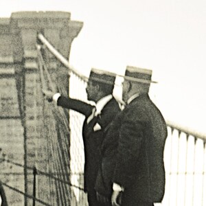 Puede incluir: Fotograf&iacute;a en tonos sepia de tres hombres con trajes y sombreros en un puente, uno de ellos se&ntilde;alando. El puente tiene un dise&ntilde;o atirantado. Los hombres est&aacute;n de pie en una pasarela con una barandilla.