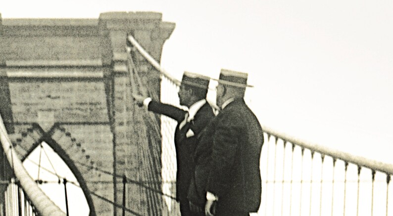 Puede incluir: Fotograf&iacute;a en tonos sepia de tres hombres con trajes y sombreros en un puente, uno de ellos se&ntilde;alando. El puente tiene un dise&ntilde;o atirantado. Los hombres est&aacute;n de pie en una pasarela con una barandilla.