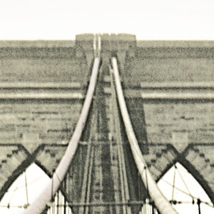 Puede incluir: Imagen en tonos sepia del puente de Brooklyn, mostrando su ic&oacute;nica arquitectura. Las torres de piedra y los cables de suspensi&oacute;n del puente son prominentes, con un cielo despejado en el fondo. La imagen captura el dise&ntilde;o sim&eacute;trico del puente.