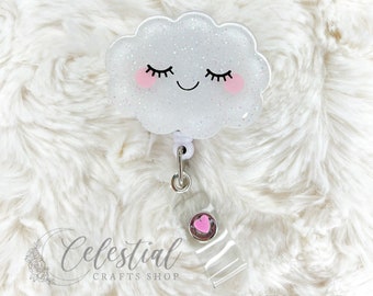 May include: A white glitter cloud with a pink heart and a smiling face, attached to a silver retractable badge holder with a pink heart charm.  Celestial Crafts Shop.