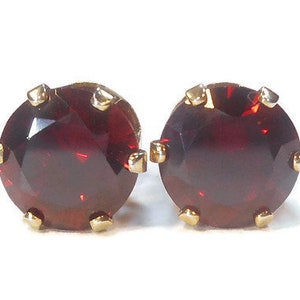 May include: A pair of gold stud earrings with round, red gemstones.