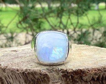 May include: A silver ring with a large, square, iridescent moonstone set in a bezel setting.