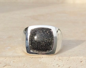May include: A silver ring with a square black gemstone set in a bezel setting.