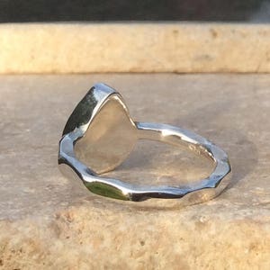 Peut inclure: Une bague en argent avec une bande textur&eacute;e et une pierre lisse de forme ovale.
