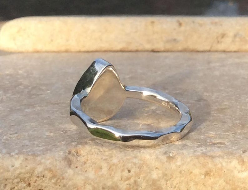 Peut inclure: Une bague en argent avec une bande textur&eacute;e et une pierre lisse de forme ovale.