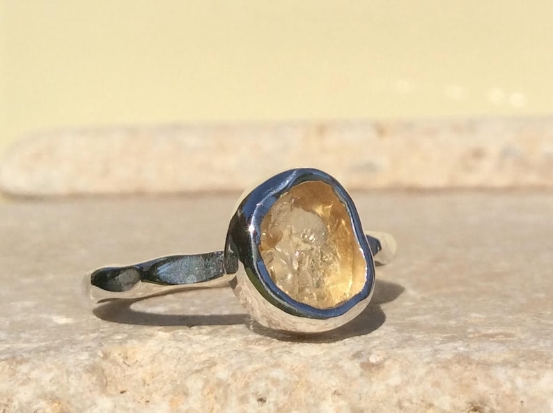 Puede incluir: Un anillo de plata con una piedra preciosa amarilla engastada en una forma irregular y &uacute;nica.