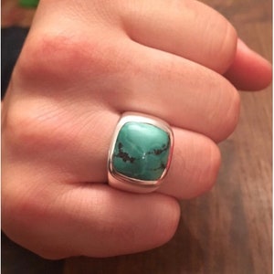 May include: A silver ring with a square turquoise stone set in a bezel setting.
